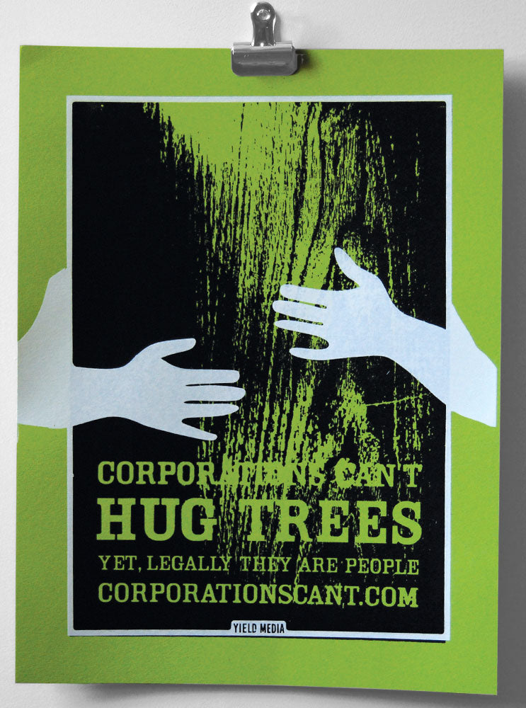 A green screen printed poster with arms reaching around a tree reading "Corporations can't hug trees. Yet, legally they are people."